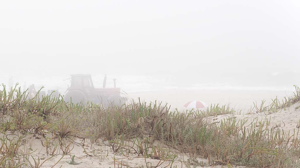 Traktor und Sonnenschirm am Strand von Costa de Lavos