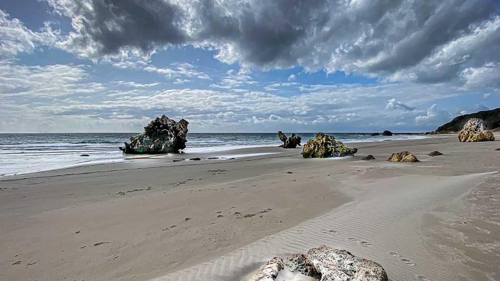 Dramatischer Himmel am Strand mit Steinen im Vordergrund